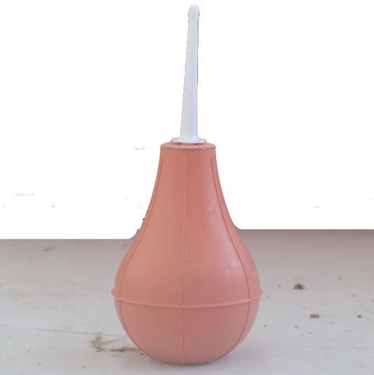 Pink enema bag with a white nozzle on a light wooden surface.