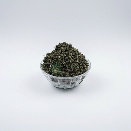 A clear glass bowl filled with dried green bitters leaf, with a watermark indicating the image was taken by 'African Grocery Online'.