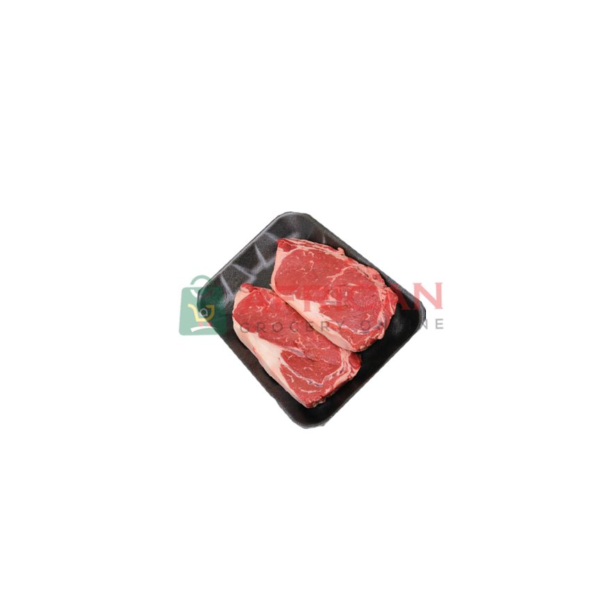 Two raw frozen steaks of cow meat on a black plate, with a brand logo in the corner.