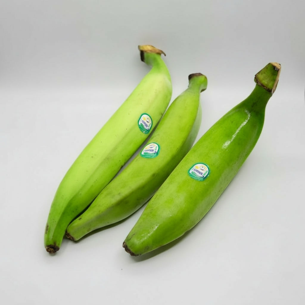 Three green bananas with stickers on a white background