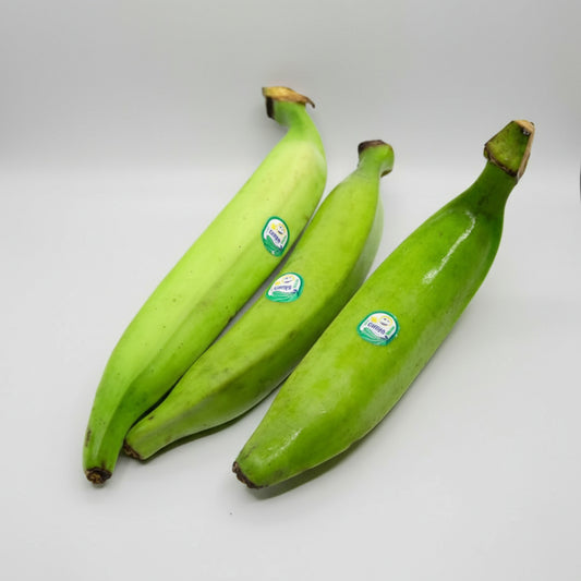 Three green bananas with stickers on a white background